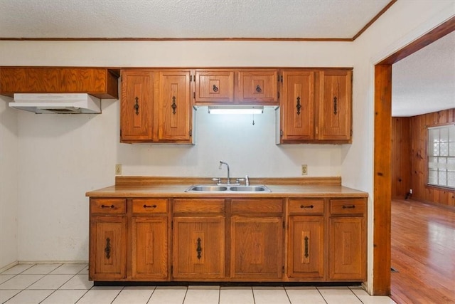 kitchen featuring crown molding, sink, light tile patterned floors, and a textured ceiling