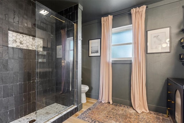 bathroom featuring tiled shower, toilet, and hardwood / wood-style flooring