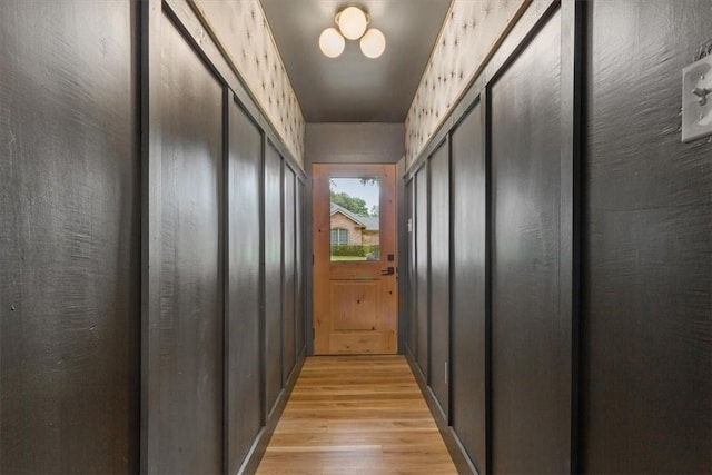 corridor featuring light hardwood / wood-style floors and wooden walls