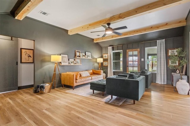 living room featuring ceiling fan, light hardwood / wood-style flooring, and beamed ceiling