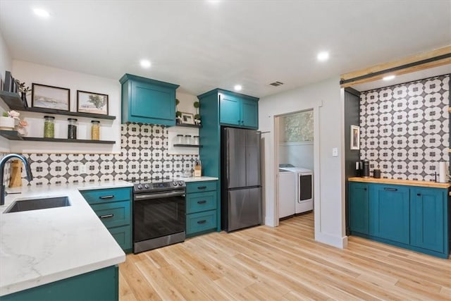 kitchen with light hardwood / wood-style flooring, sink, stainless steel appliances, and washing machine and clothes dryer