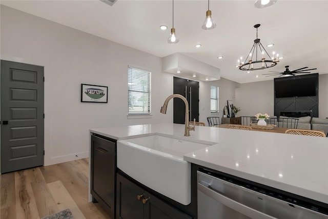 kitchen with sink, light hardwood / wood-style flooring, stainless steel dishwasher, decorative light fixtures, and ceiling fan with notable chandelier