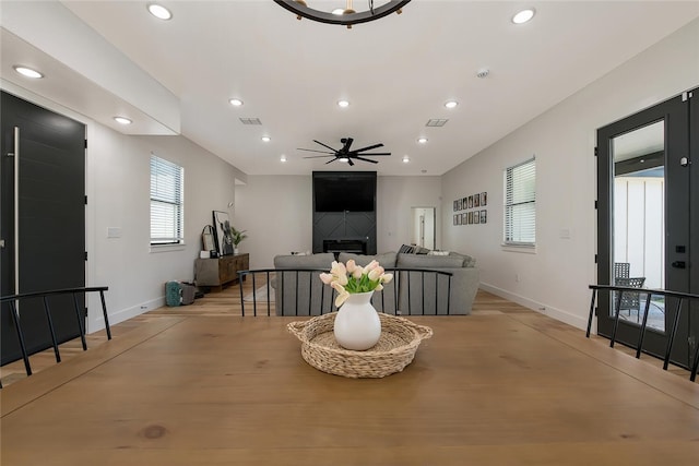 dining room featuring ceiling fan, a fireplace, and light hardwood / wood-style floors