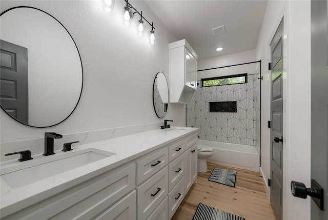 full bathroom featuring toilet, vanity, wood-type flooring, and tiled shower / bath