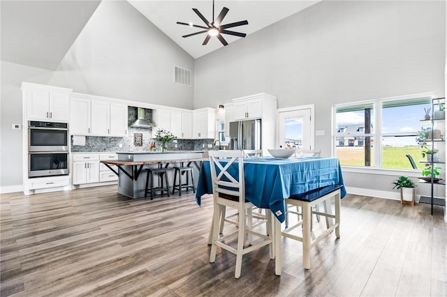 dining space featuring ceiling fan, sink, light hardwood / wood-style flooring, and high vaulted ceiling