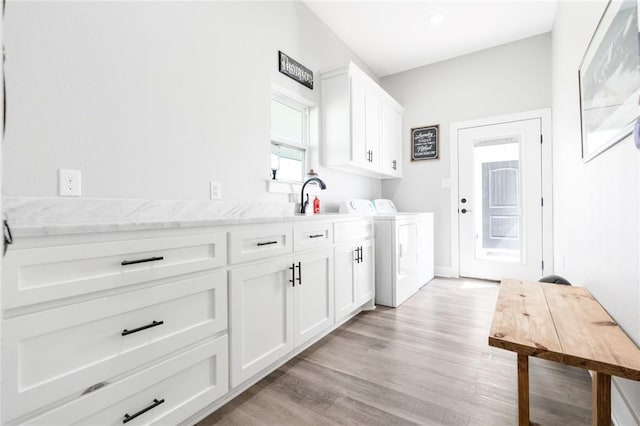 laundry room with sink, independent washer and dryer, light hardwood / wood-style floors, and cabinets