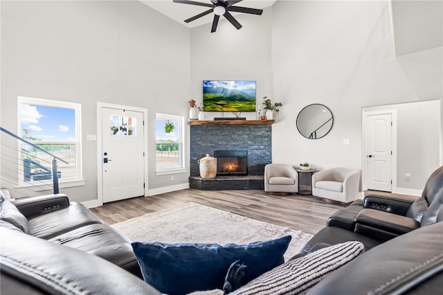 living room featuring high vaulted ceiling, plenty of natural light, a stone fireplace, and light hardwood / wood-style flooring