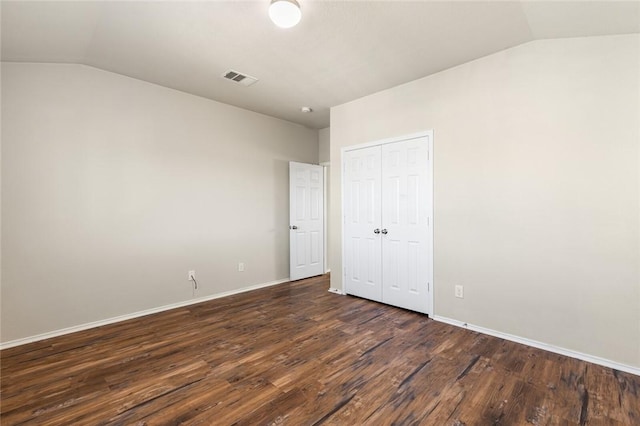 unfurnished bedroom featuring dark hardwood / wood-style floors, a closet, and lofted ceiling