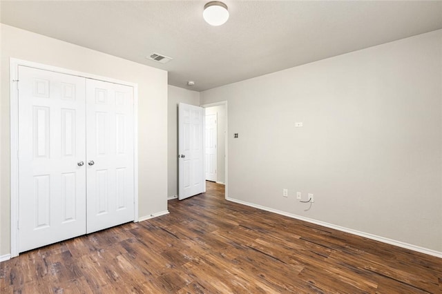 unfurnished bedroom featuring a closet and dark hardwood / wood-style floors