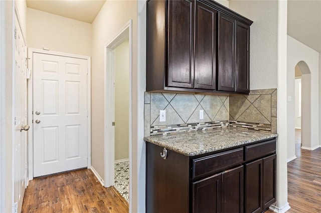 kitchen with light stone countertops, dark brown cabinets, and dark hardwood / wood-style floors