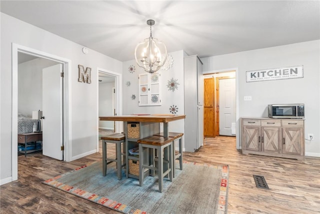 dining room with hardwood / wood-style floors and an inviting chandelier