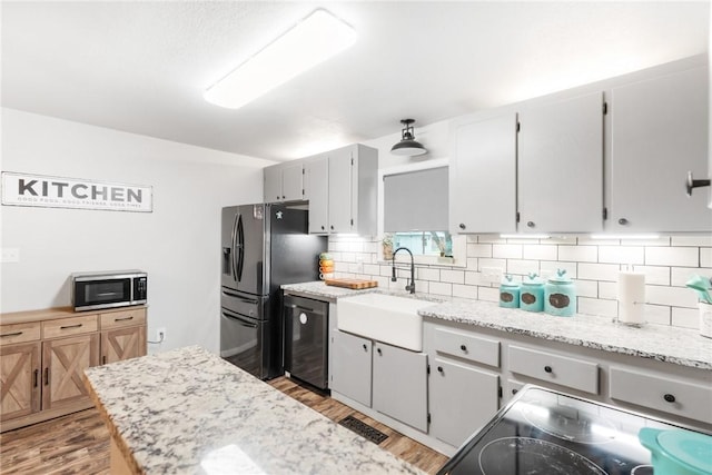 kitchen featuring appliances with stainless steel finishes, wood-type flooring, sink, backsplash, and light stone countertops