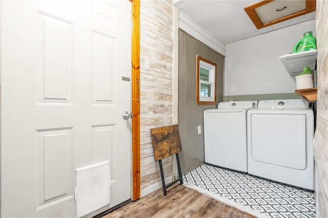 laundry room featuring washing machine and clothes dryer and light hardwood / wood-style flooring