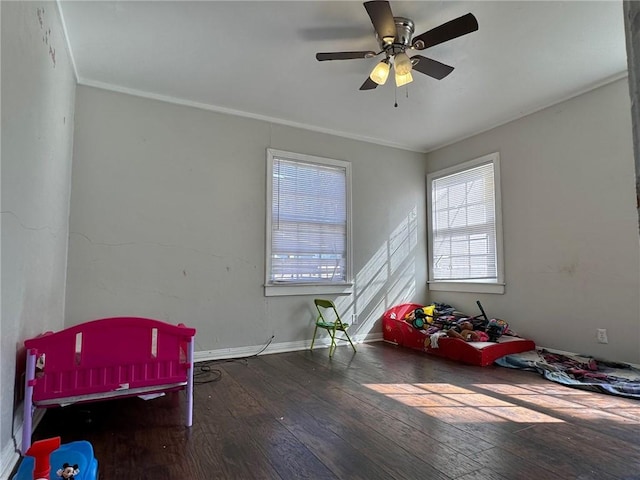 playroom featuring dark hardwood / wood-style flooring, ceiling fan, and crown molding