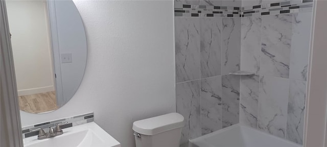 full bathroom featuring tiled shower / bath, toilet, sink, and tasteful backsplash