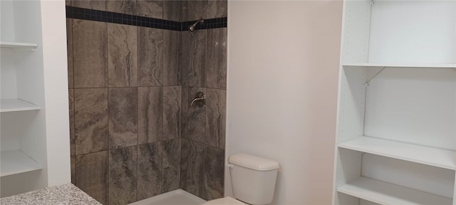 bathroom featuring toilet and a tile shower