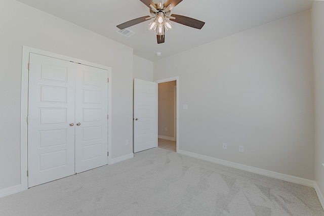 unfurnished bedroom featuring ceiling fan, a closet, and light colored carpet