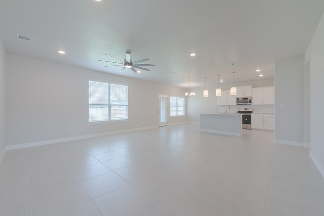 unfurnished living room featuring sink, light tile patterned flooring, and ceiling fan with notable chandelier