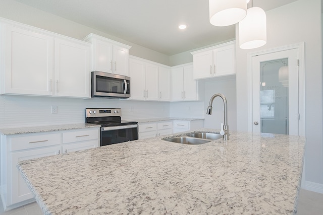 kitchen featuring pendant lighting, white cabinets, sink, decorative backsplash, and appliances with stainless steel finishes