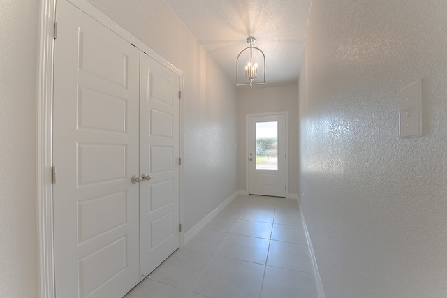 entryway featuring a textured ceiling, a notable chandelier, and light tile patterned flooring