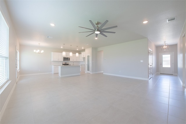 unfurnished living room featuring light tile patterned floors and ceiling fan with notable chandelier