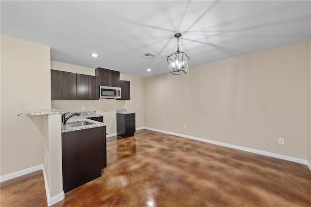 kitchen with stainless steel microwave, a sink, visible vents, and baseboards