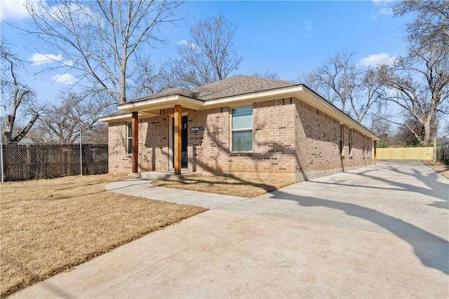 view of front of home featuring concrete driveway, brick siding, and fence