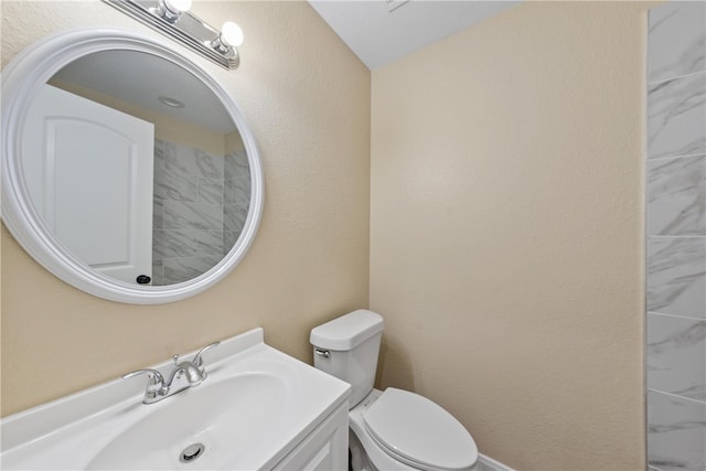 bathroom with a textured wall, vanity, and toilet