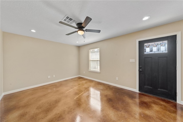 foyer entrance with finished concrete flooring, baseboards, visible vents, a ceiling fan, and a textured ceiling