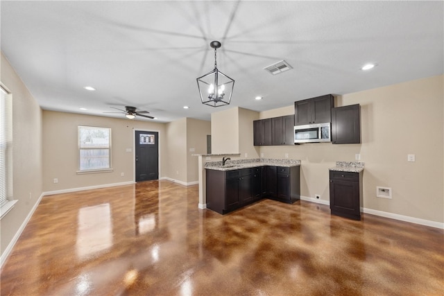 kitchen featuring stainless steel microwave, visible vents, finished concrete floors, a sink, and baseboards