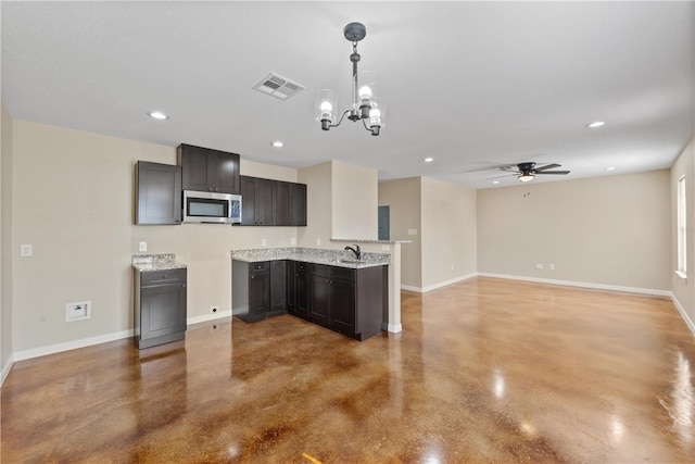 kitchen featuring stainless steel microwave, visible vents, baseboards, and finished concrete flooring