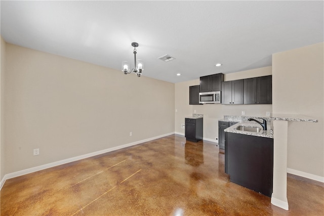 kitchen featuring baseboards, visible vents, stainless steel microwave, finished concrete floors, and a sink