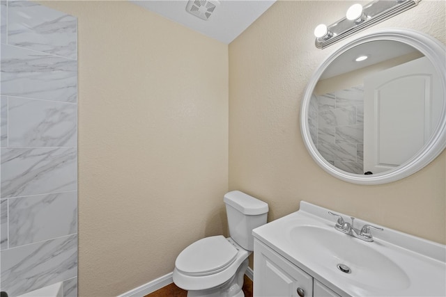 bathroom featuring toilet, a textured wall, vanity, and visible vents