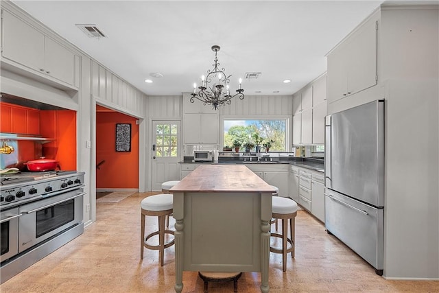 kitchen with a kitchen bar, appliances with stainless steel finishes, pendant lighting, an inviting chandelier, and a center island