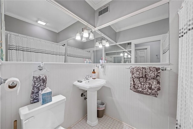 bathroom with toilet, ornamental molding, and wooden walls