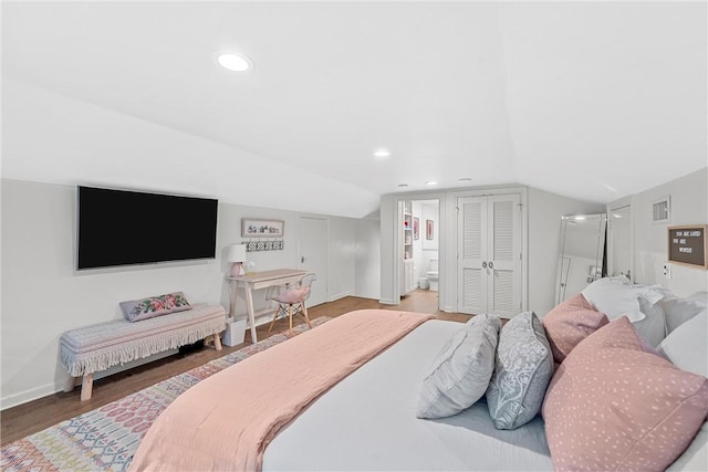 bedroom with hardwood / wood-style floors, lofted ceiling, and connected bathroom