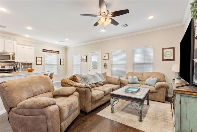 living room featuring hardwood / wood-style floors, ceiling fan, a healthy amount of sunlight, and ornamental molding