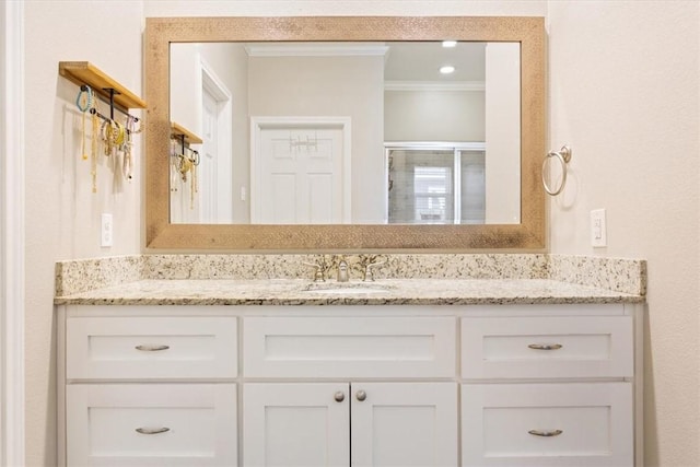 bathroom featuring vanity, a shower with shower door, and crown molding