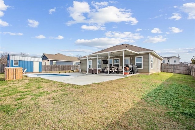 back of house with a lawn, a patio, a fenced in pool, and a storage shed