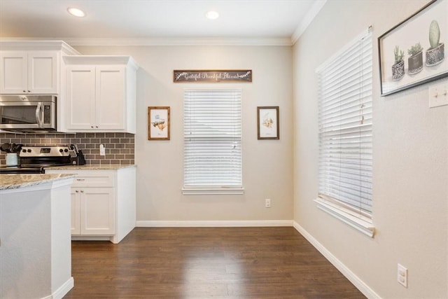 kitchen with white cabinets, appliances with stainless steel finishes, decorative backsplash, and light stone countertops