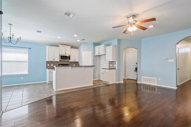 unfurnished living room featuring dark hardwood / wood-style floors and ceiling fan with notable chandelier