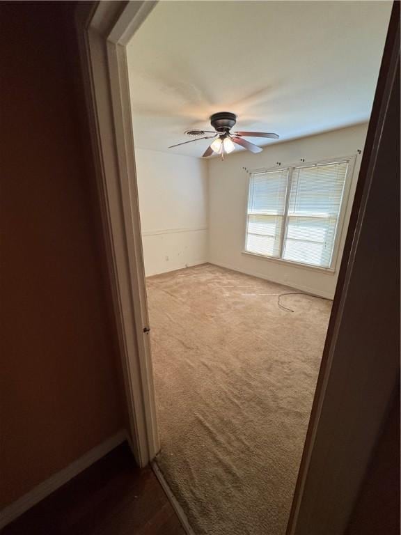 unfurnished room with ceiling fan and dark colored carpet