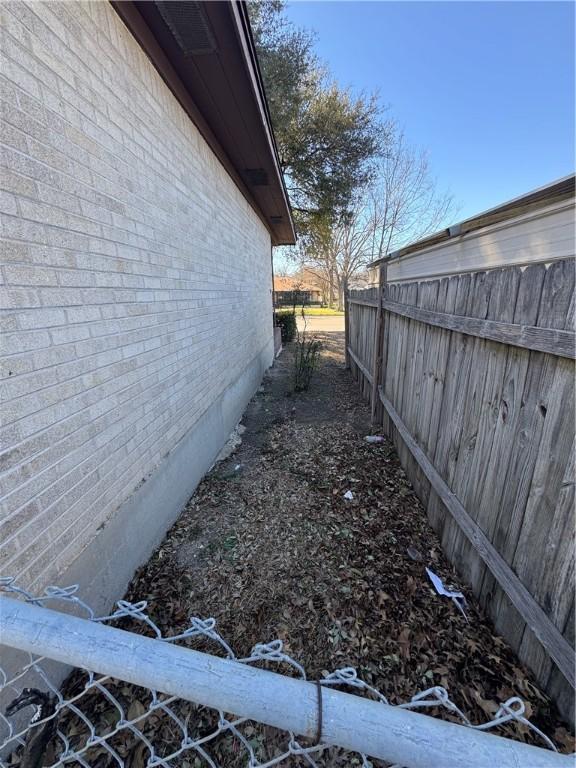 view of property exterior featuring brick siding and fence