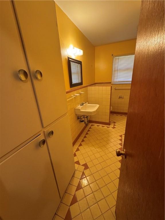 bathroom with a sink, tile patterned floors, tile walls, and wainscoting