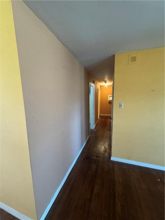 corridor featuring baseboards, visible vents, and wood finished floors