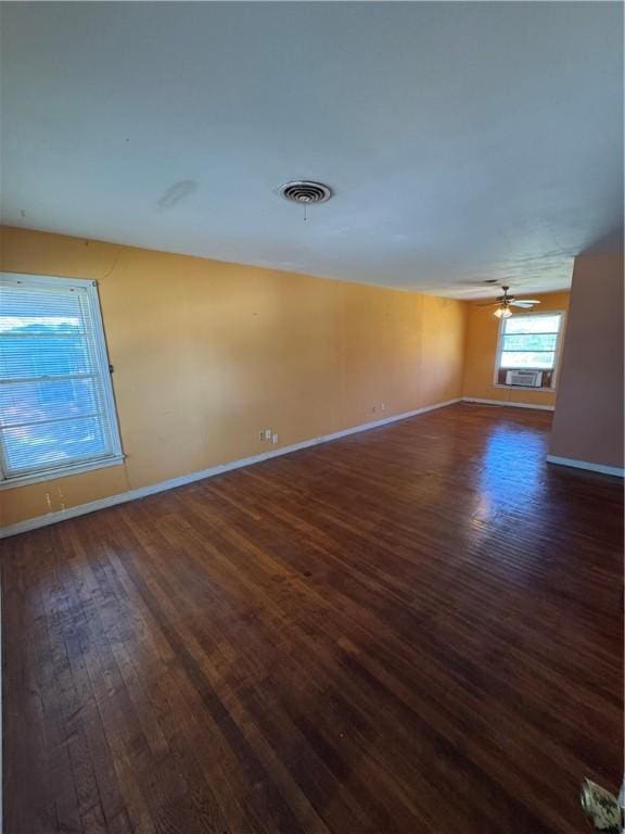 spare room featuring baseboards, ceiling fan, visible vents, and dark wood-type flooring