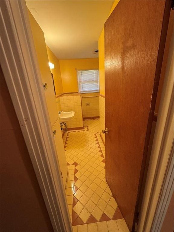 bathroom featuring tile patterned flooring, wainscoting, a sink, and tile walls