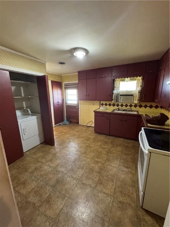 kitchen with white electric stove, a sink, visible vents, backsplash, and washer / dryer