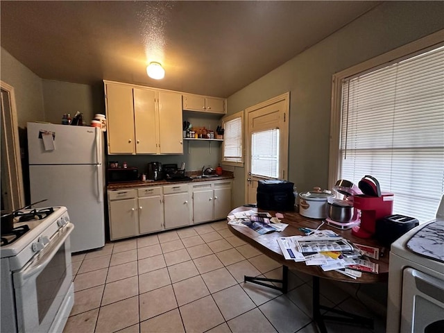 kitchen featuring washer / dryer, white appliances, sink, and light tile patterned floors