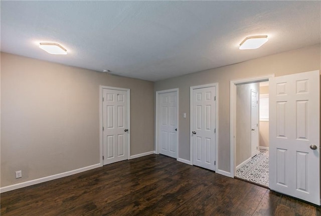 unfurnished bedroom featuring multiple closets and dark hardwood / wood-style flooring